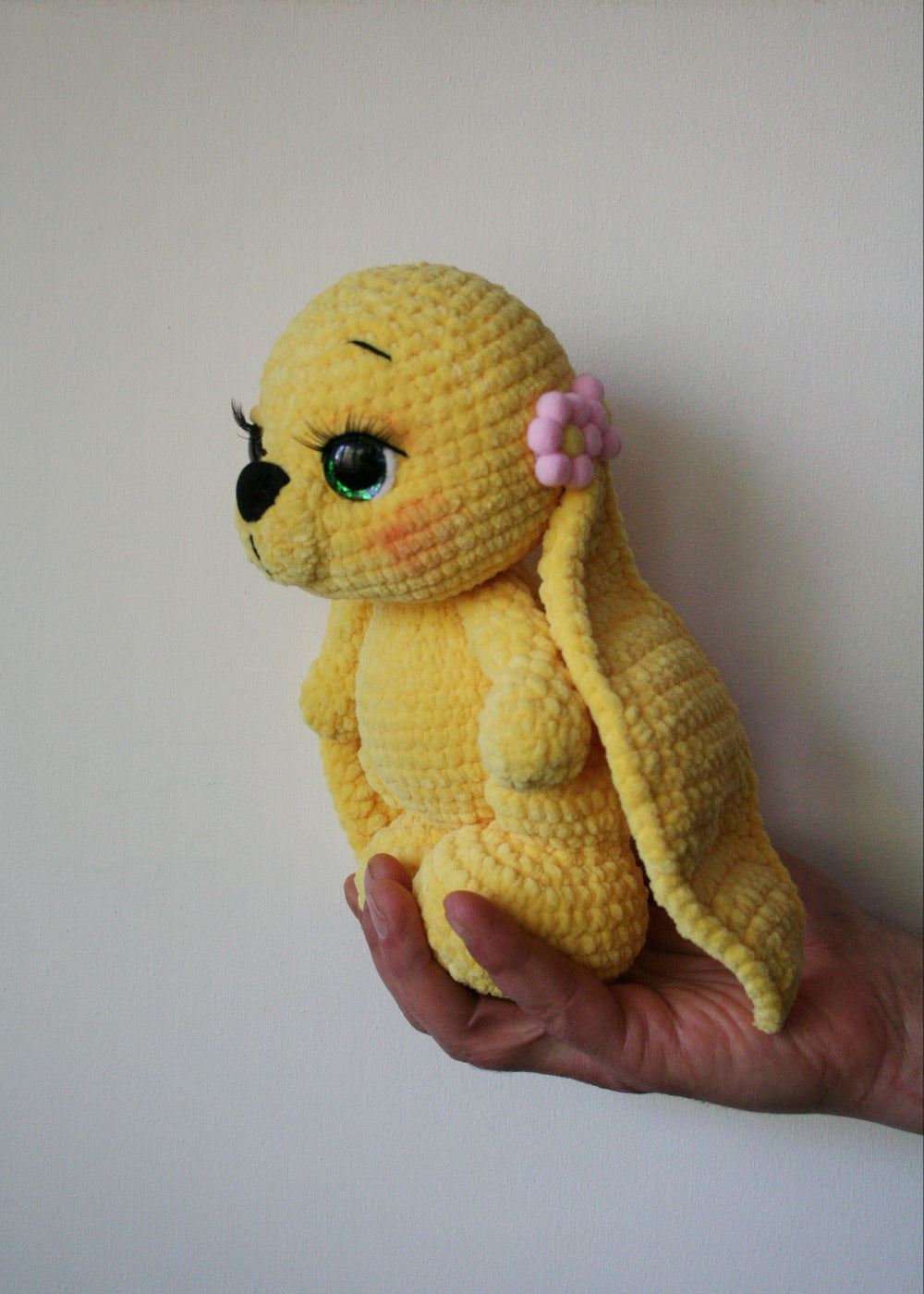 Detail of long soft ears on a handmade yellow plush rabbit, high-quality amigurumi craftsmanship