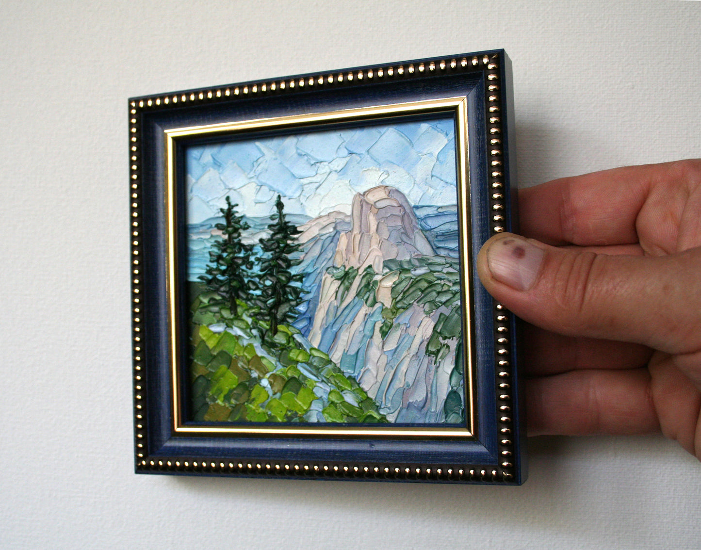 Framed miniature landscape painting held by a hand 
