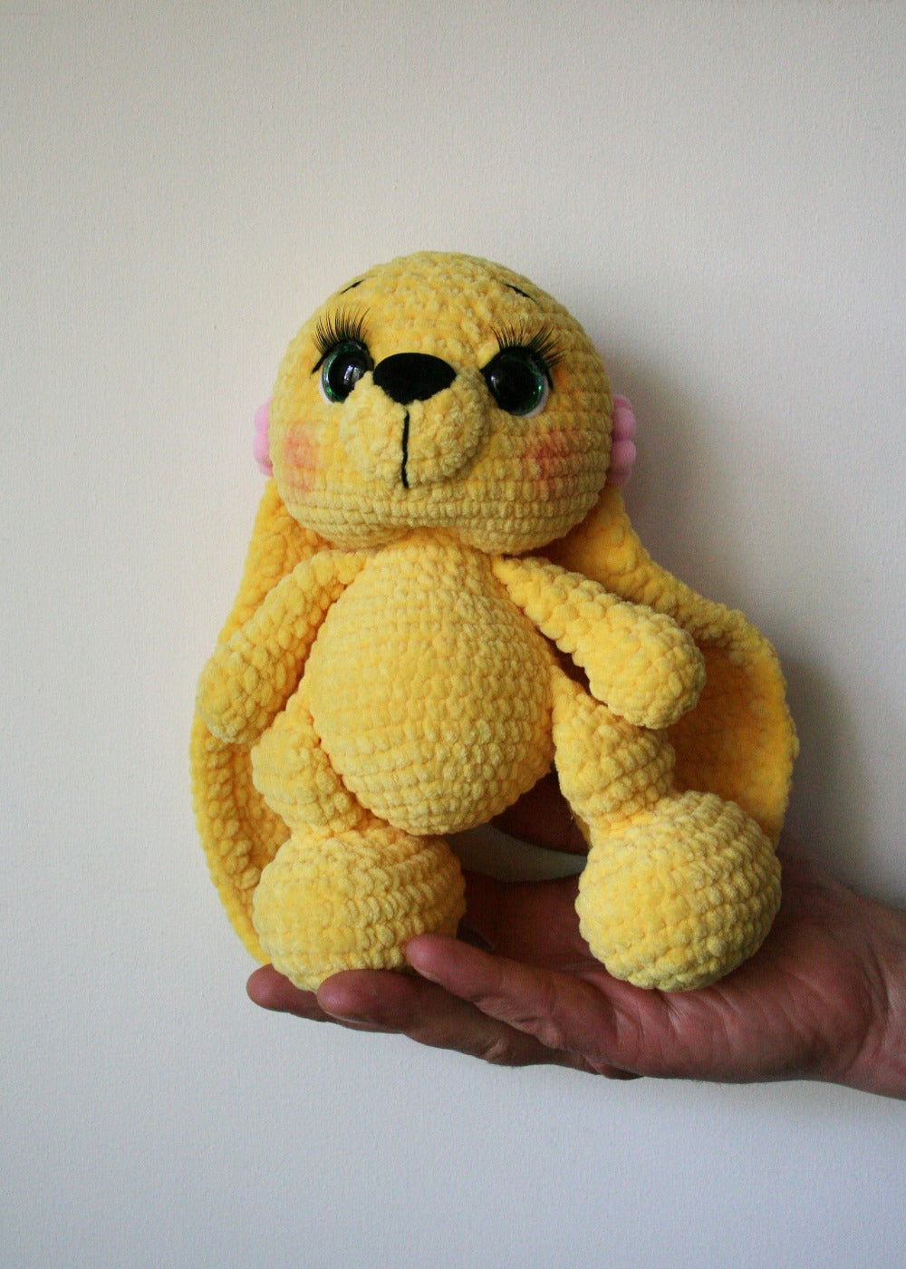 Handheld view of a 23cm yellow stuffed rabbit toy, one-of-a-kind crochet gift from Original Sisters' Art.