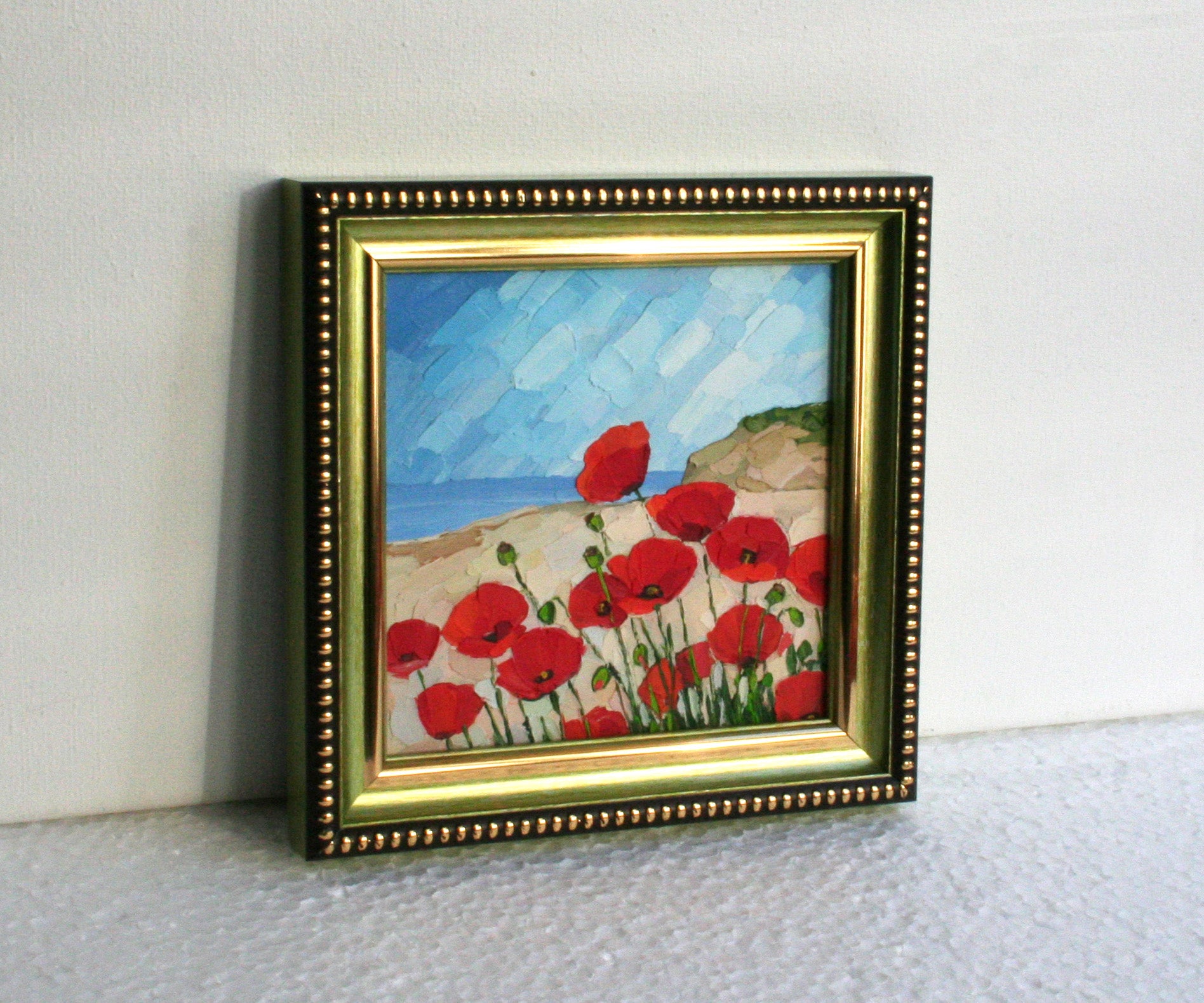 Framed painting of red flowers on a white surface