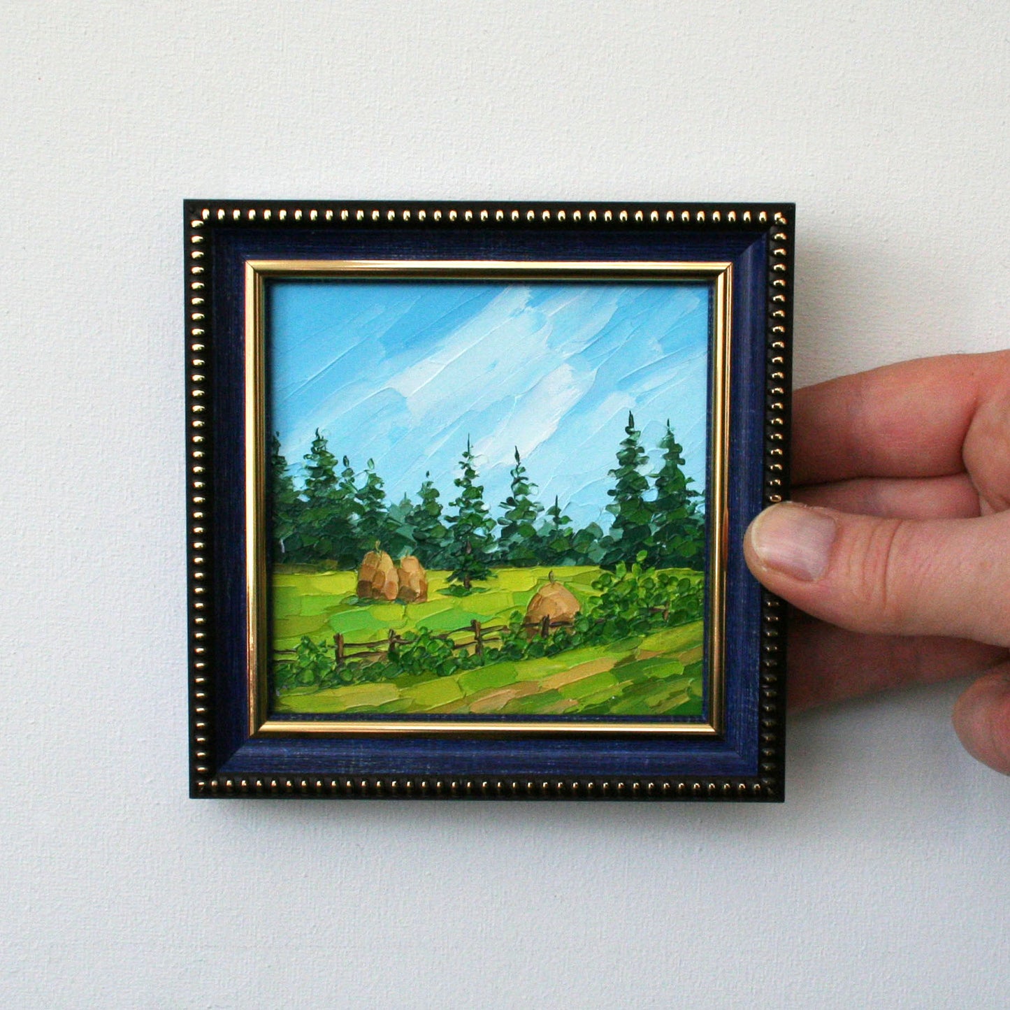 Small landscape painting in a blue frame