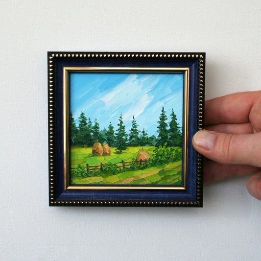 Small landscape painting in a blue frame