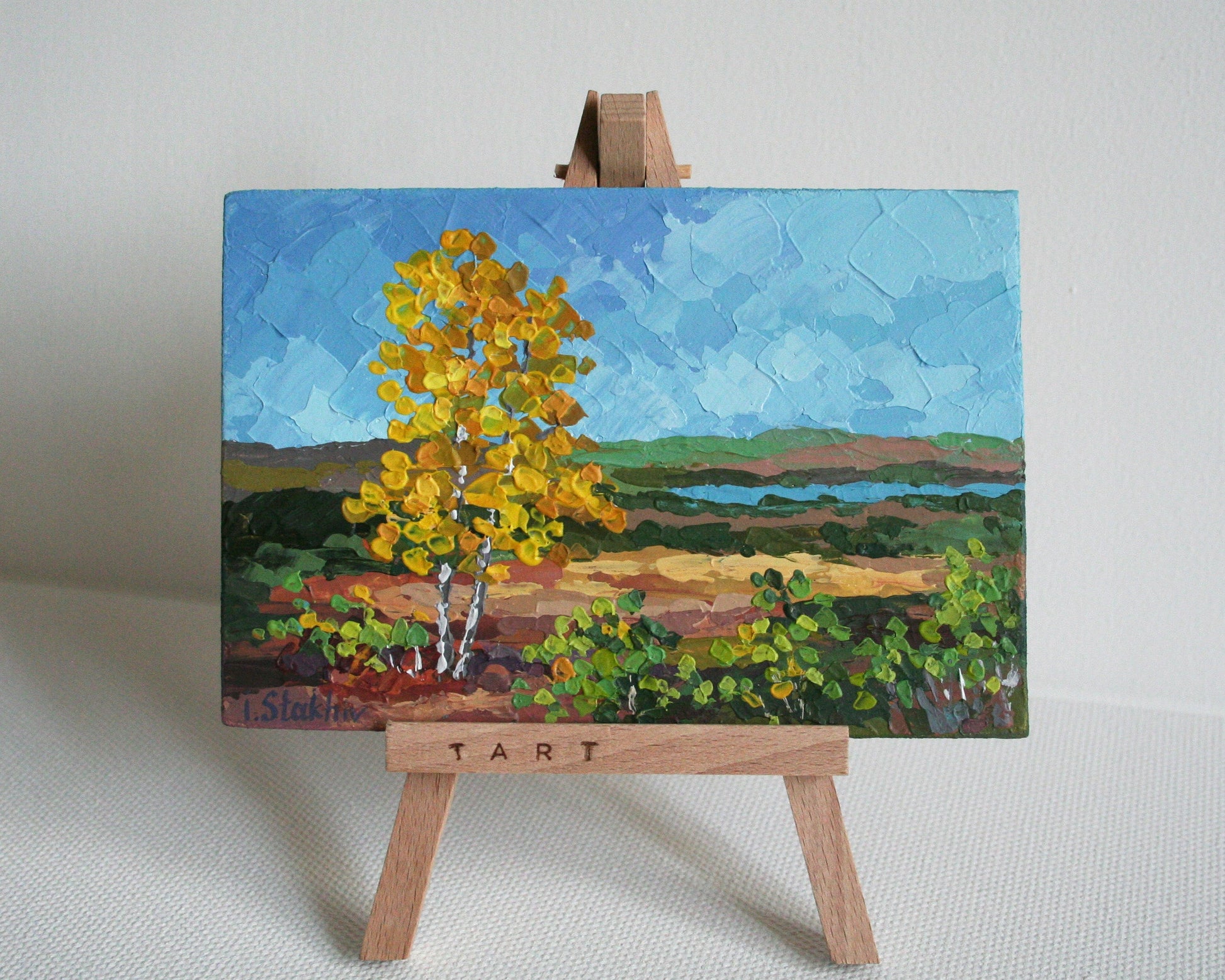 Painting of a landscape with a yellow tree on a wooden easel