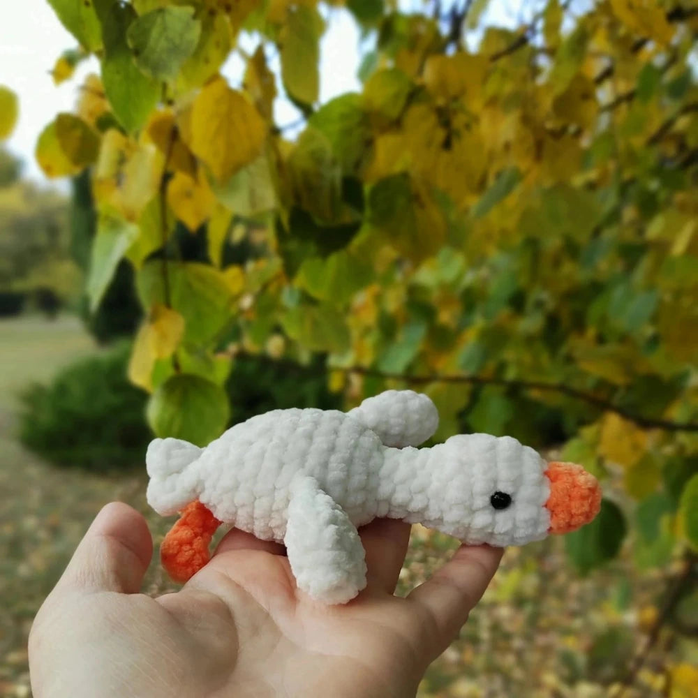 Small crochet goose plush toy in hand, white chenille yarn, orange accents, handmade amigurumi 14cm