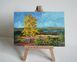 Painting of autumn landscape with a yellow tree on a wooden easel